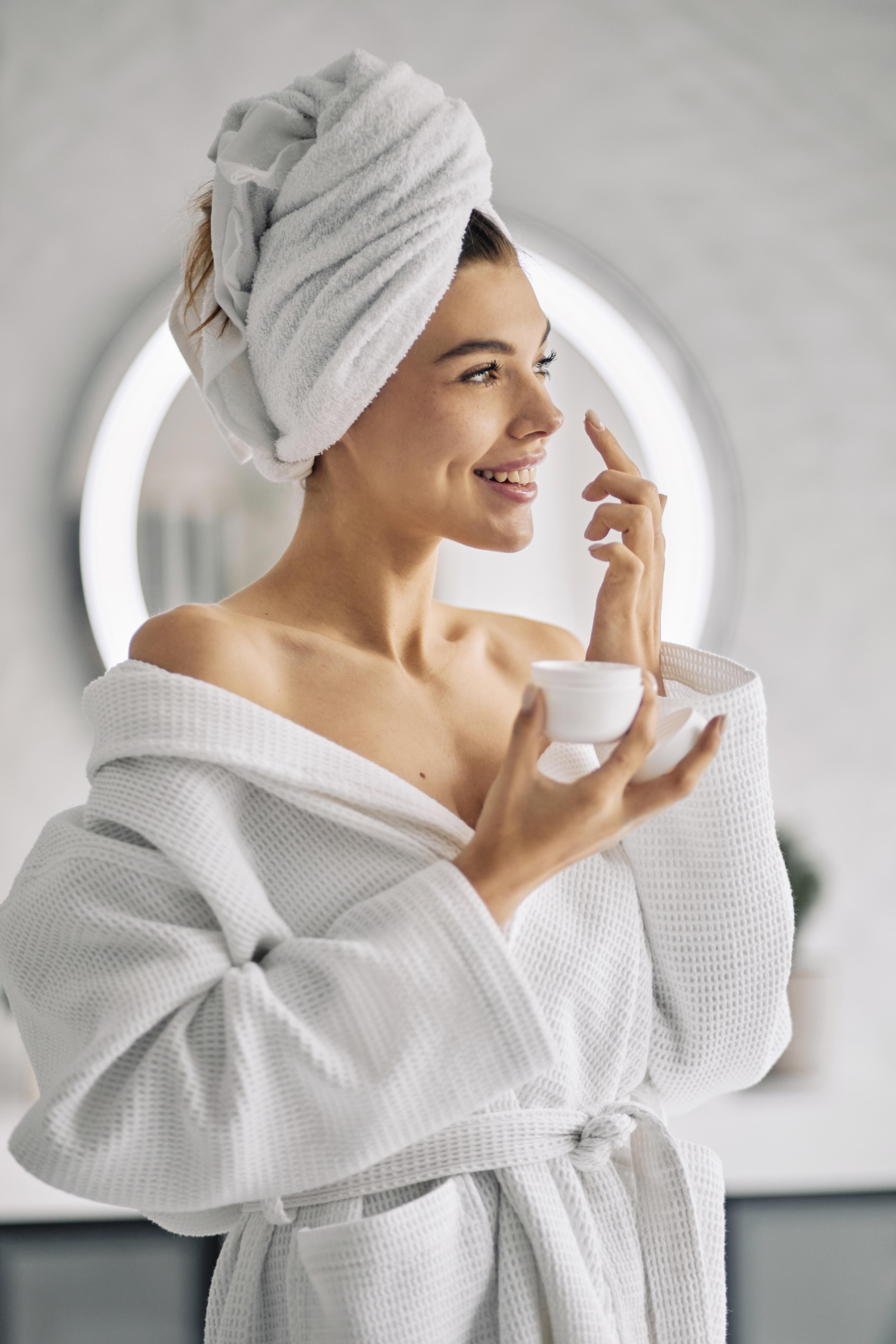 smiley woman holding skincare cream c4a97